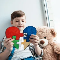 An autistic boy holds a puzzle heart as a sign of solidarity with people suffering from autism